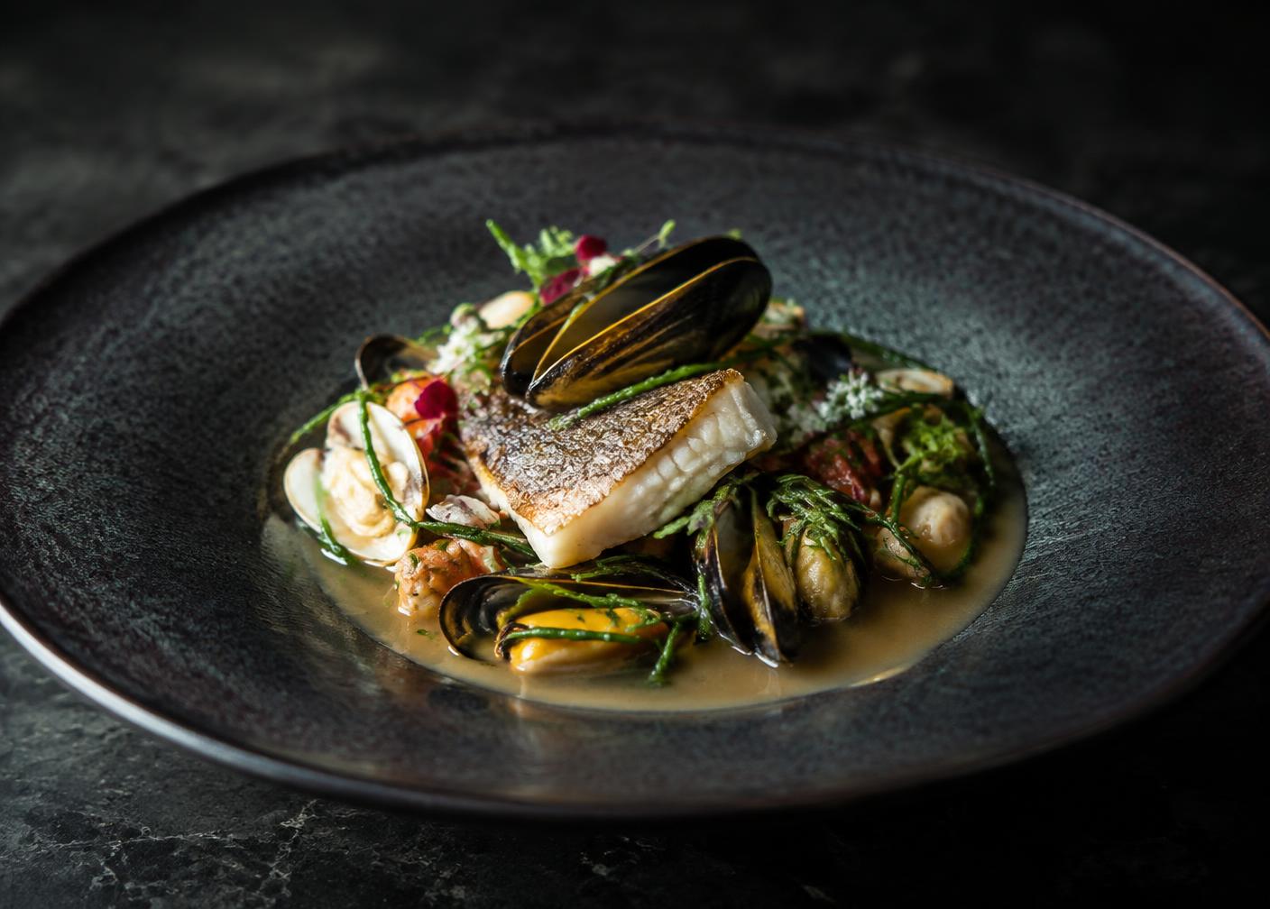 Line caught fish with shellfish and sea herbs in a shallow broth