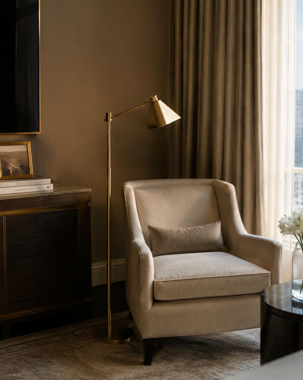 Quiet corner of a suite with a linen armchair and brass reading lamp