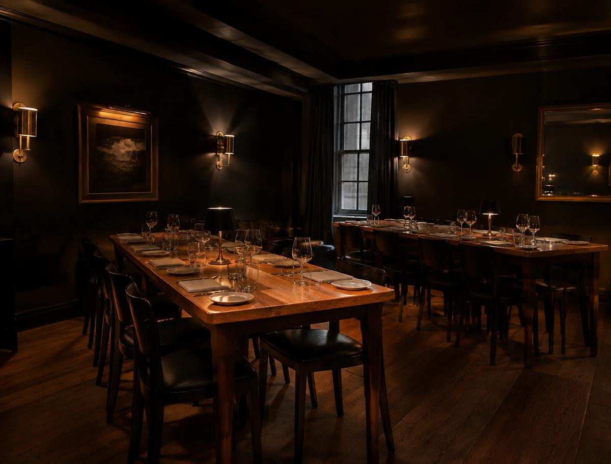 Dining room with dark walls, long oak tables and brass sconces